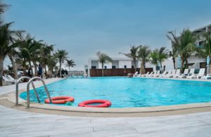 Un camping moderne à Fréjus avec une grande piscine entourée de chaises longues et d'une végétation luxuriante.